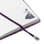 Notebook with a purple ribbon bookmark featuring a decorative clasp on a white background