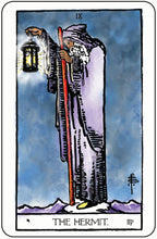 Tarot card featuring a figure known as 'The Hermit' holding a staff and lantern against a blue sky.