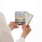 Person holding a card with a scenic design and text on a white background