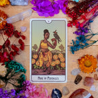 Nine of Pentacles tarot card surrounded by flowers and crystals on a wooden surface