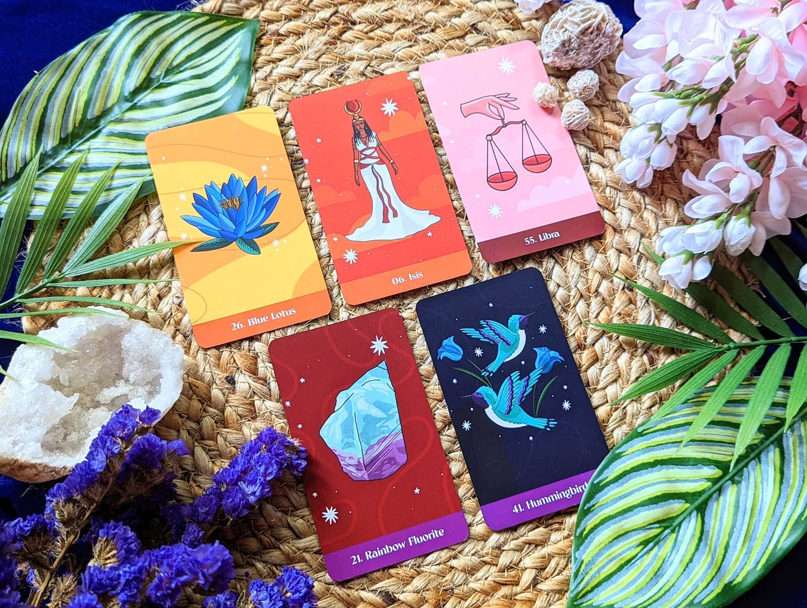 Five tarot cards on a woven surface with flowers and leaves.