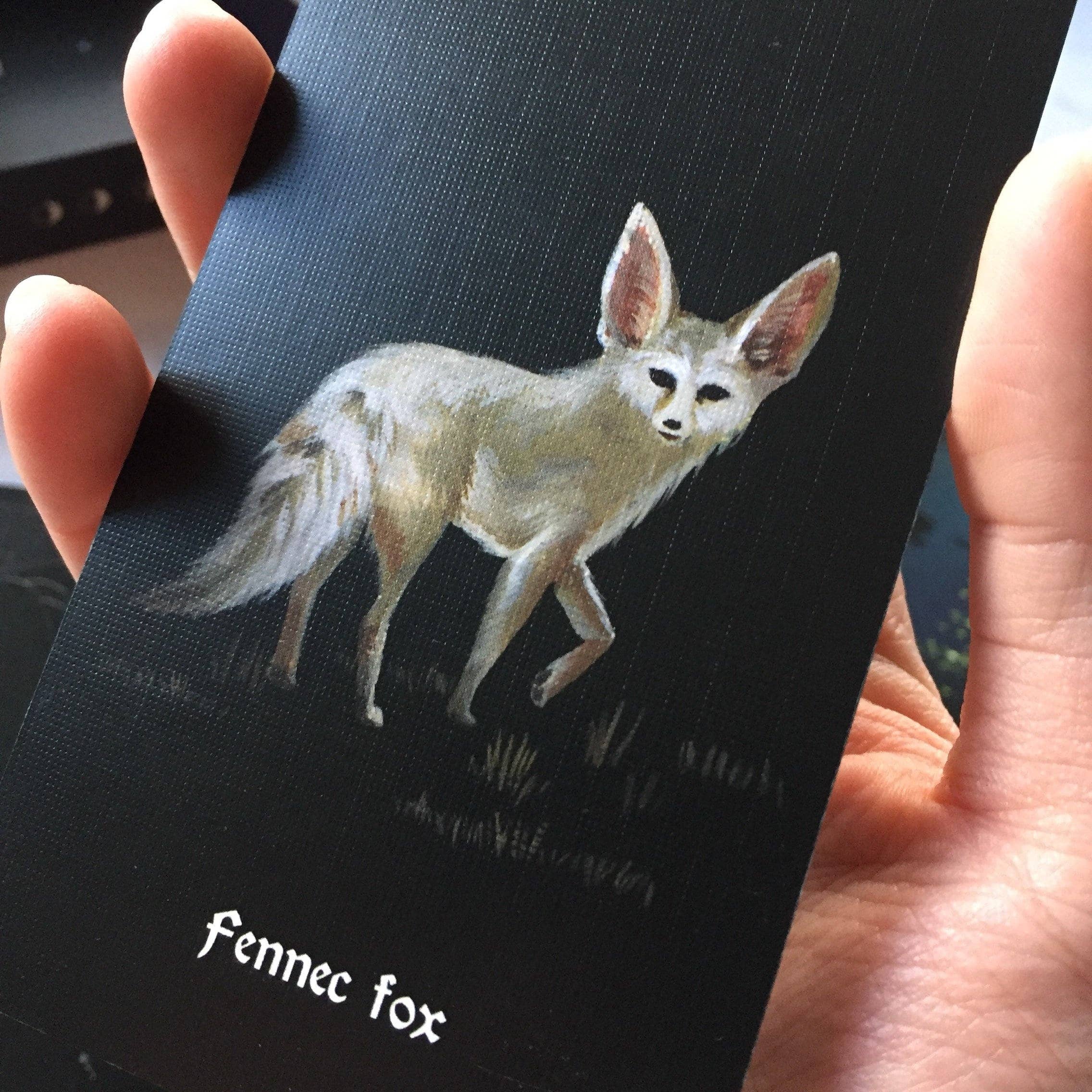 Hand holding a card with a fennec fox illustration and text.