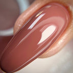 Close-up of a glossy beige nail polish on a white background