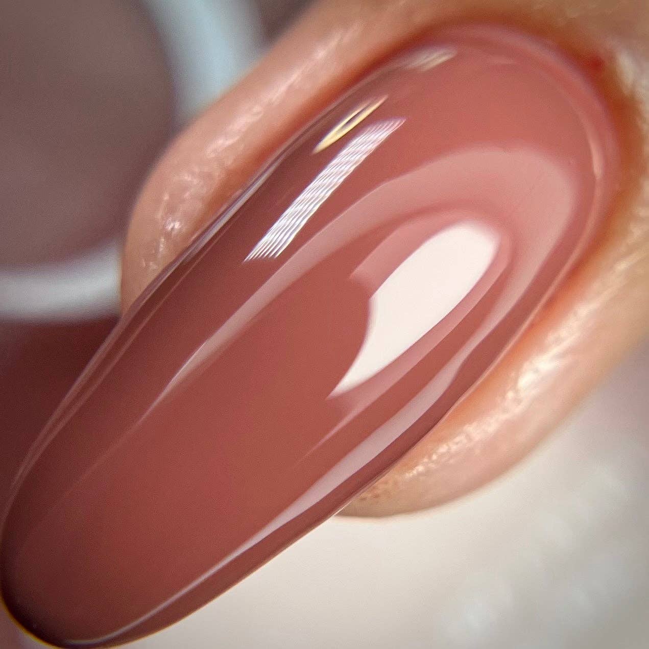 Close-up of a glossy beige nail polish on a white background