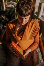 Person holding a small orange bag with floral patterns indoors
