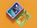 Two tarot cards on an orange background, one with a cat and ghost illustration and the other with a fox and tree illustration.