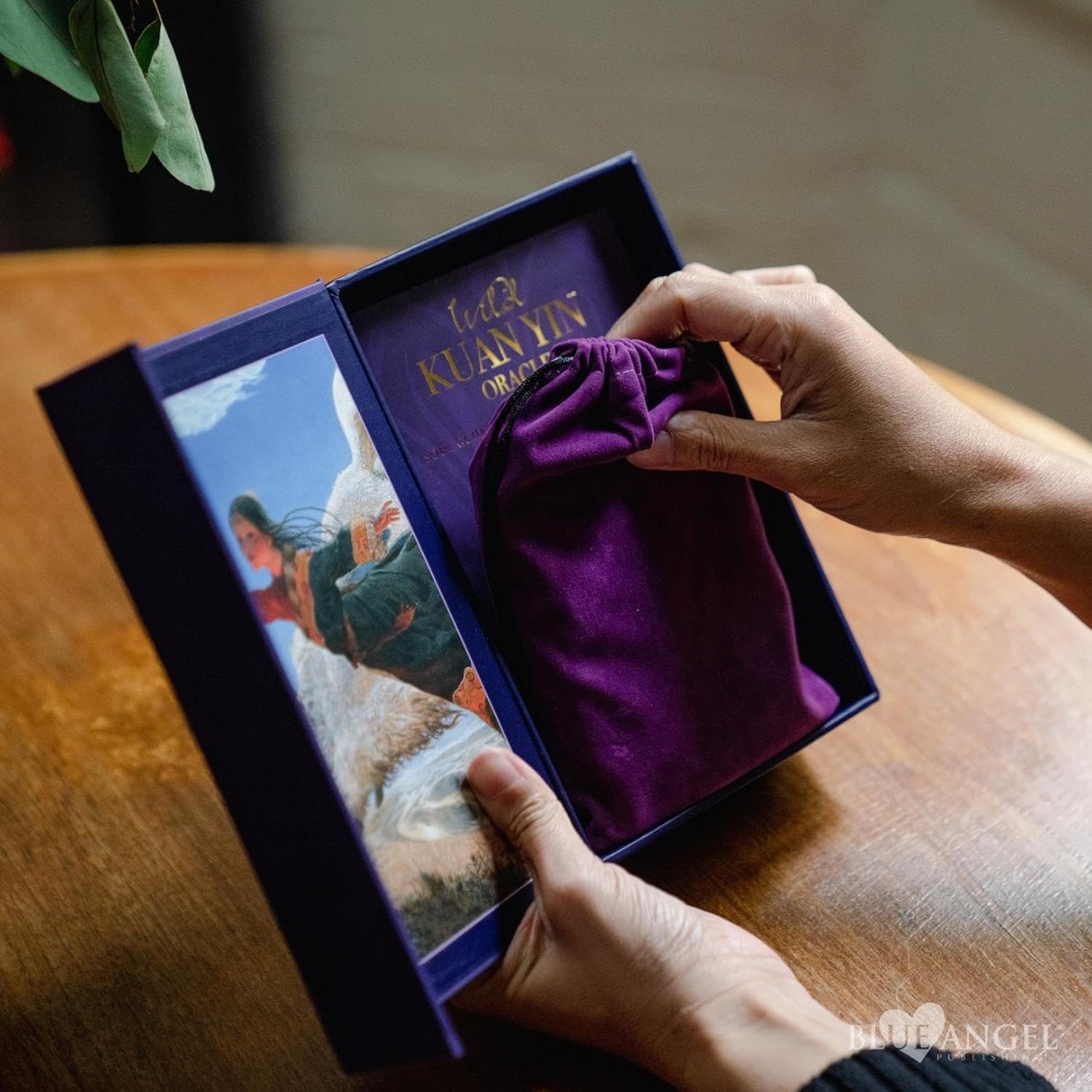 Person opening a purple box with a figurine inside on a wooden surface