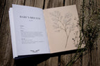 Open book with text and illustration of baby's breath on a wooden surface