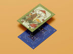 Two tarot cards on a beige background, one green with a bear and flowers, the other blue with cat illustrations.