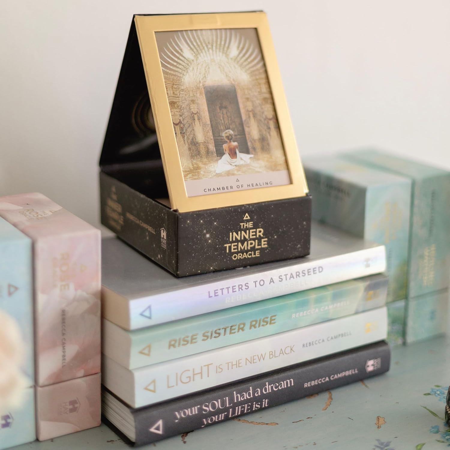 Stack of books with a decorative box labeled 'The Inner Temple Oracle' on a light surface.