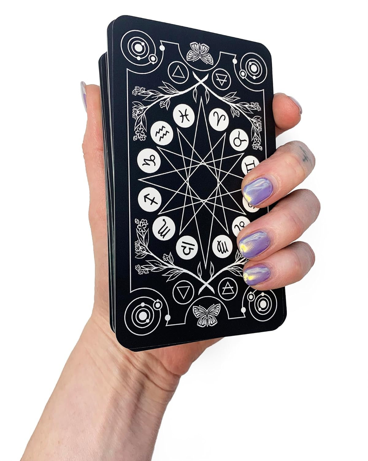 Hand holding a black card with white symbols and designs on a white background