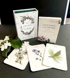 Books and card decks titled 'Listening to Flowers' on a dark surface with floral illustrations.