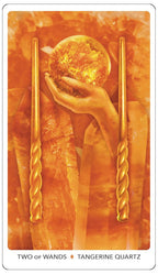 Two of Wands tarot card with a hand holding a crystal ball and two gold wands, featuring Tangerine Quartz.