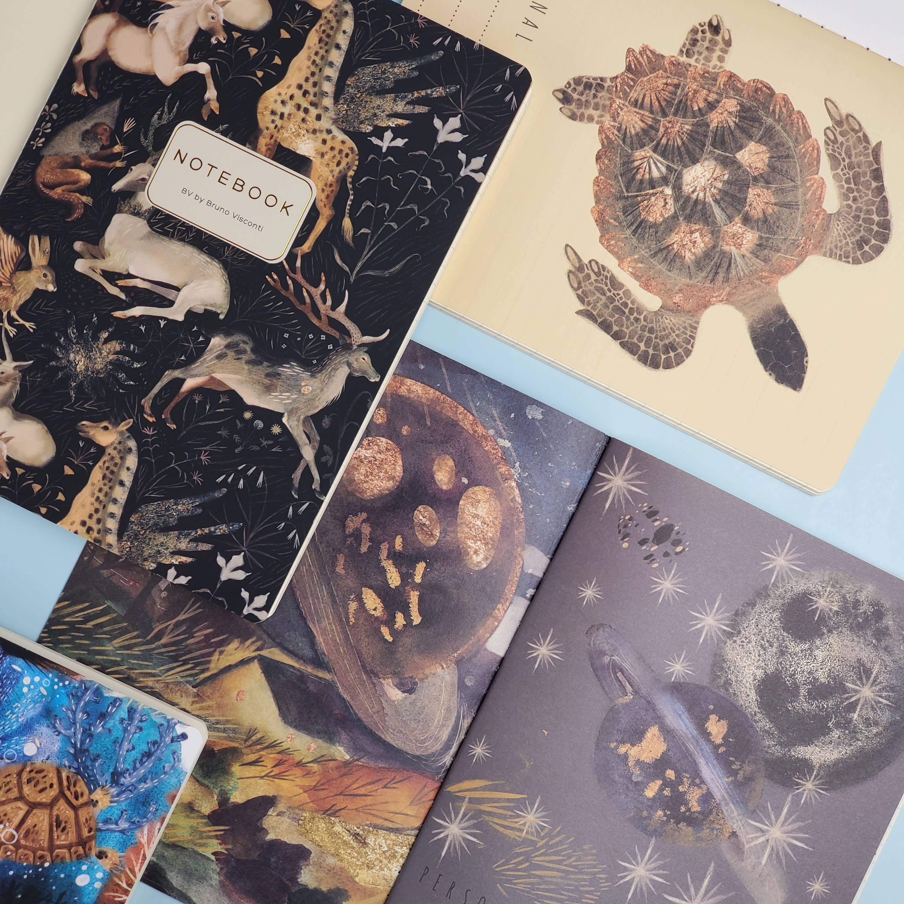 Collection of notebooks with various designs including animals and celestial patterns.