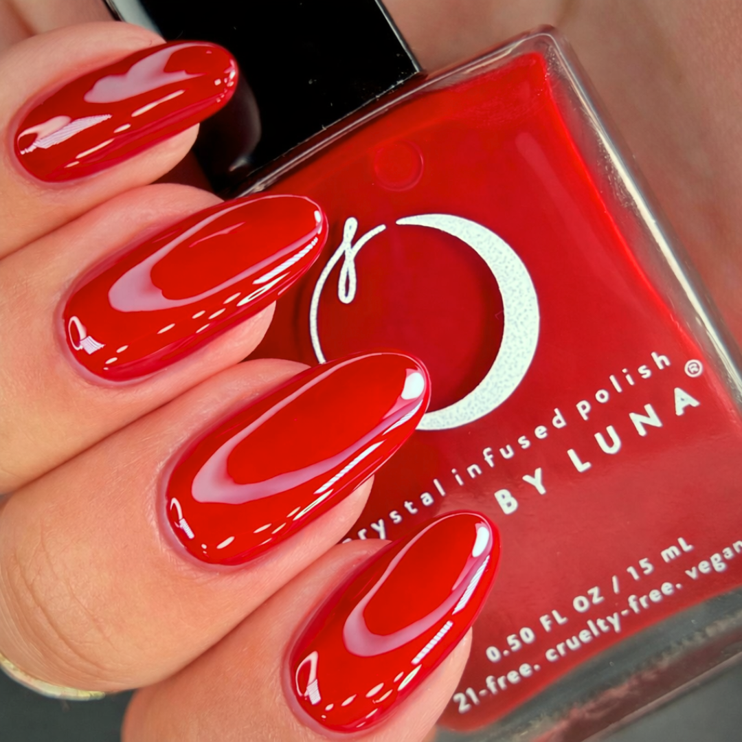 Red nail polish with a bottle of Luna nail polish in the background