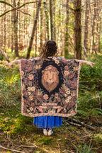 Person holding a tapestry with a lion design in a forest