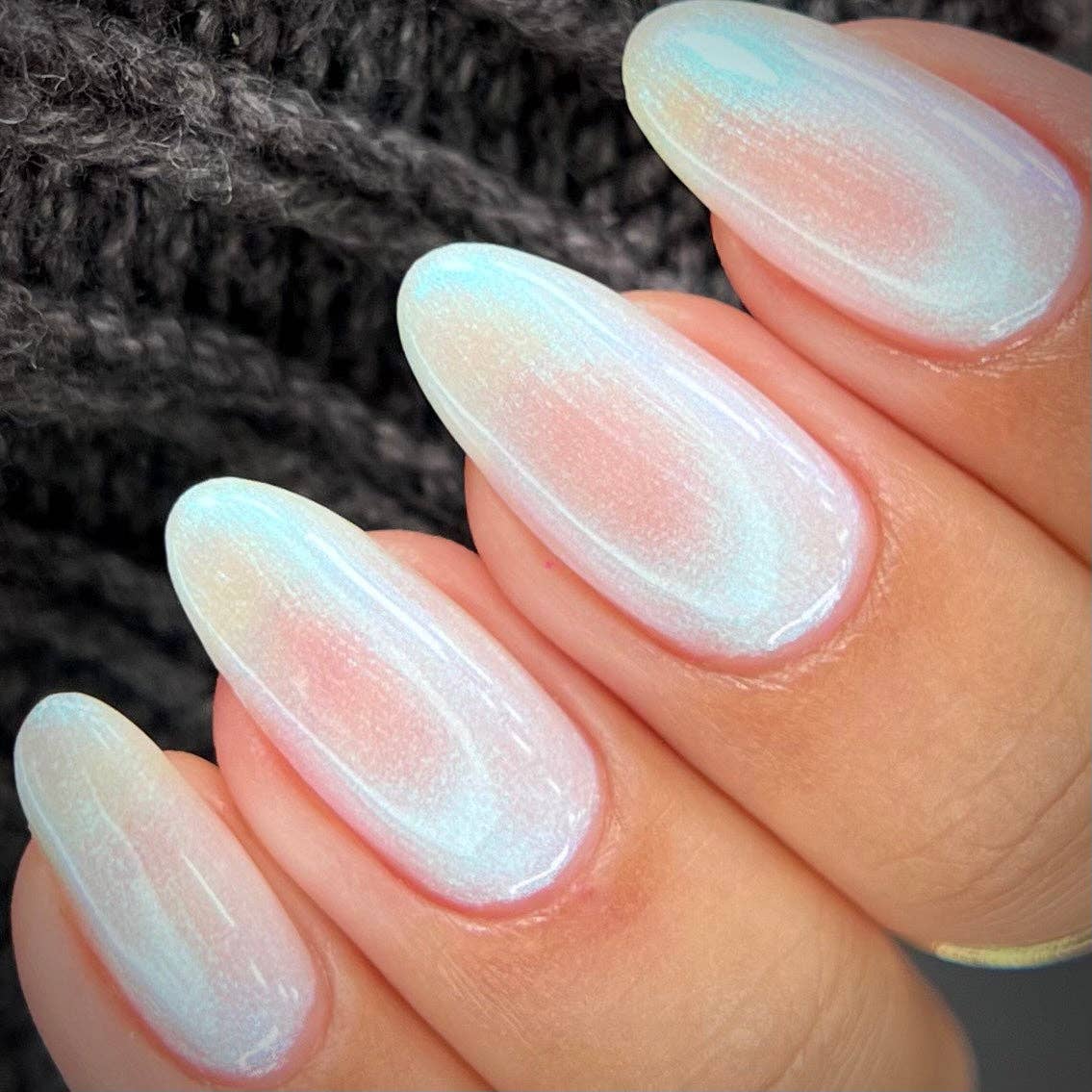 Close-up of a hand with gradient nail polish on a dark textured background