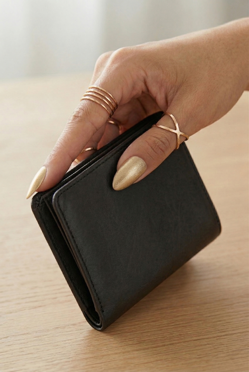 Hand holding a black wallet on a wooden surface