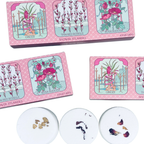 Shower steamers with botanical designs in pink packaging on a white background