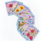 A fan arrangement of illustrated botanical cards on a white background, showing flower and berry designs with pastel purple borders and labels such as echinacea, lemon balm, sunflower, one, raspberry, and ten.