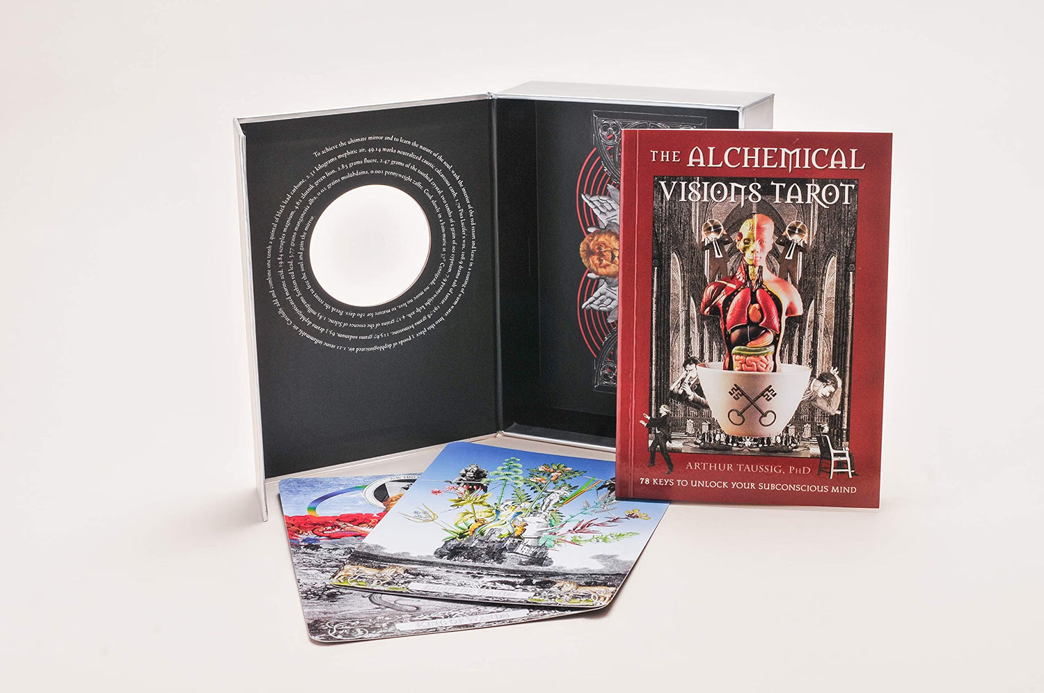 The Alchemical Visions Tarot deck displayed open on a white background, showing the black inner booklet with a circular cutout, the red outer box cover, and several illustrated tarot cards spread in front.
