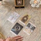 Four tarot cards on a textured surface with a hand reaching towards them.