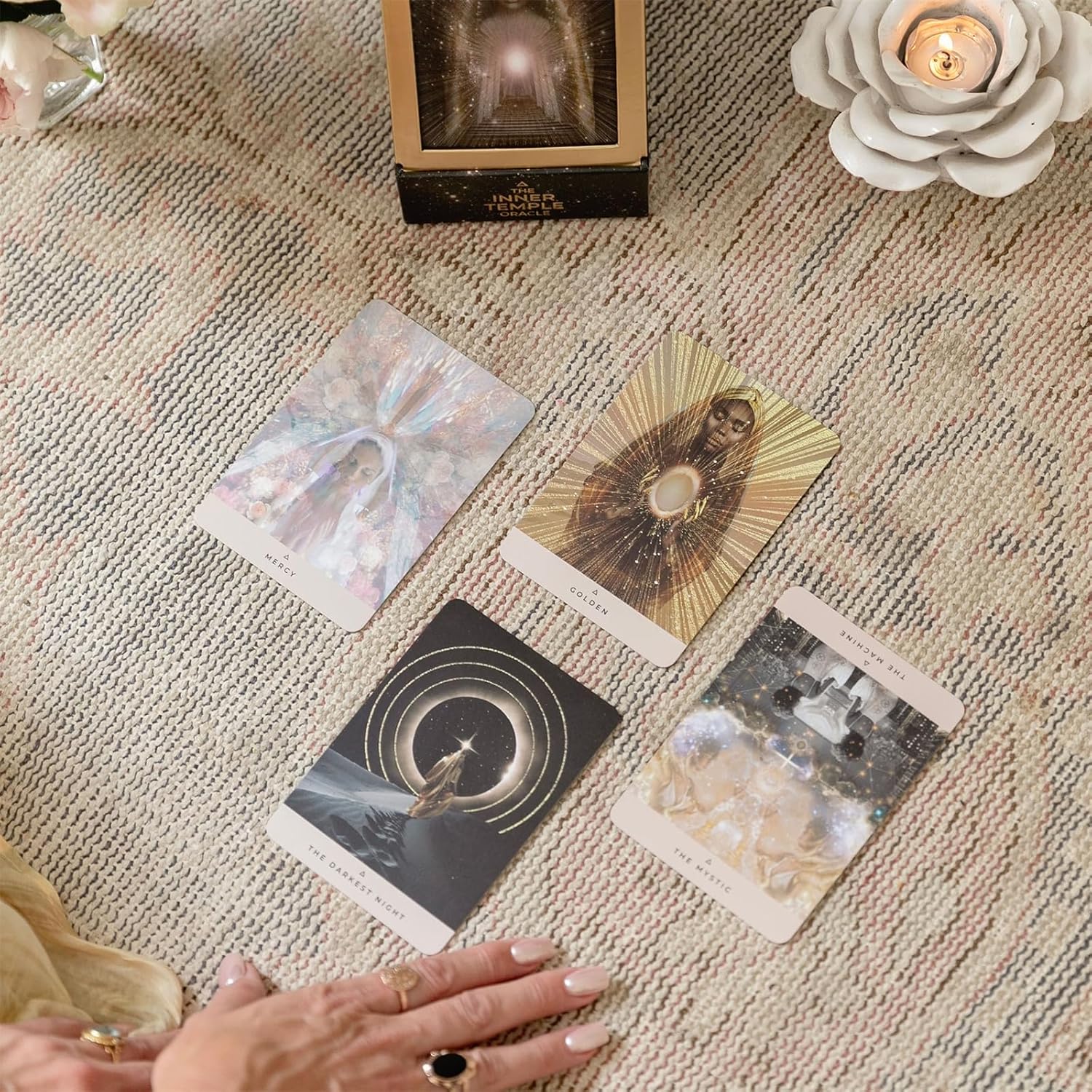 Four tarot cards on a textured surface with a hand reaching towards them.
