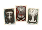 Three illustrated tarot-style cards are arranged side by side on a plain white background. The left card is dark blue-gray with a layered chalice and raindrop motif; the center card is cream with red border, a dripping heart, and a bowl motif; the right card is cream with a tree-like figure and green border.