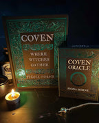 Two books titled 'Coven' and 'Coven Oracle' by Fiona Horne on a dark surface with a lit candle.