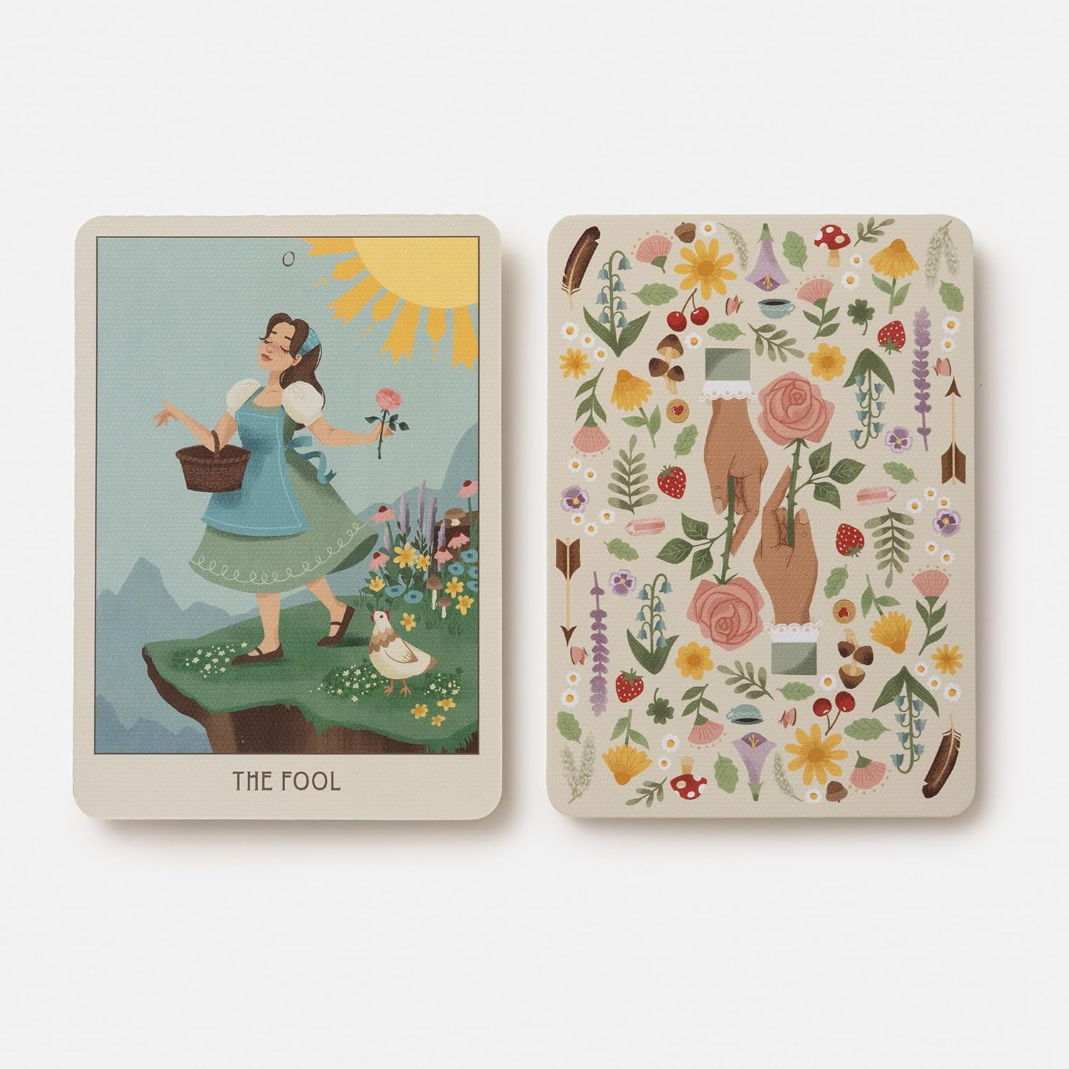 Two tarot cards, one featuring 'The Fool' with a woman in a garden and the other with floral and nature-themed design.