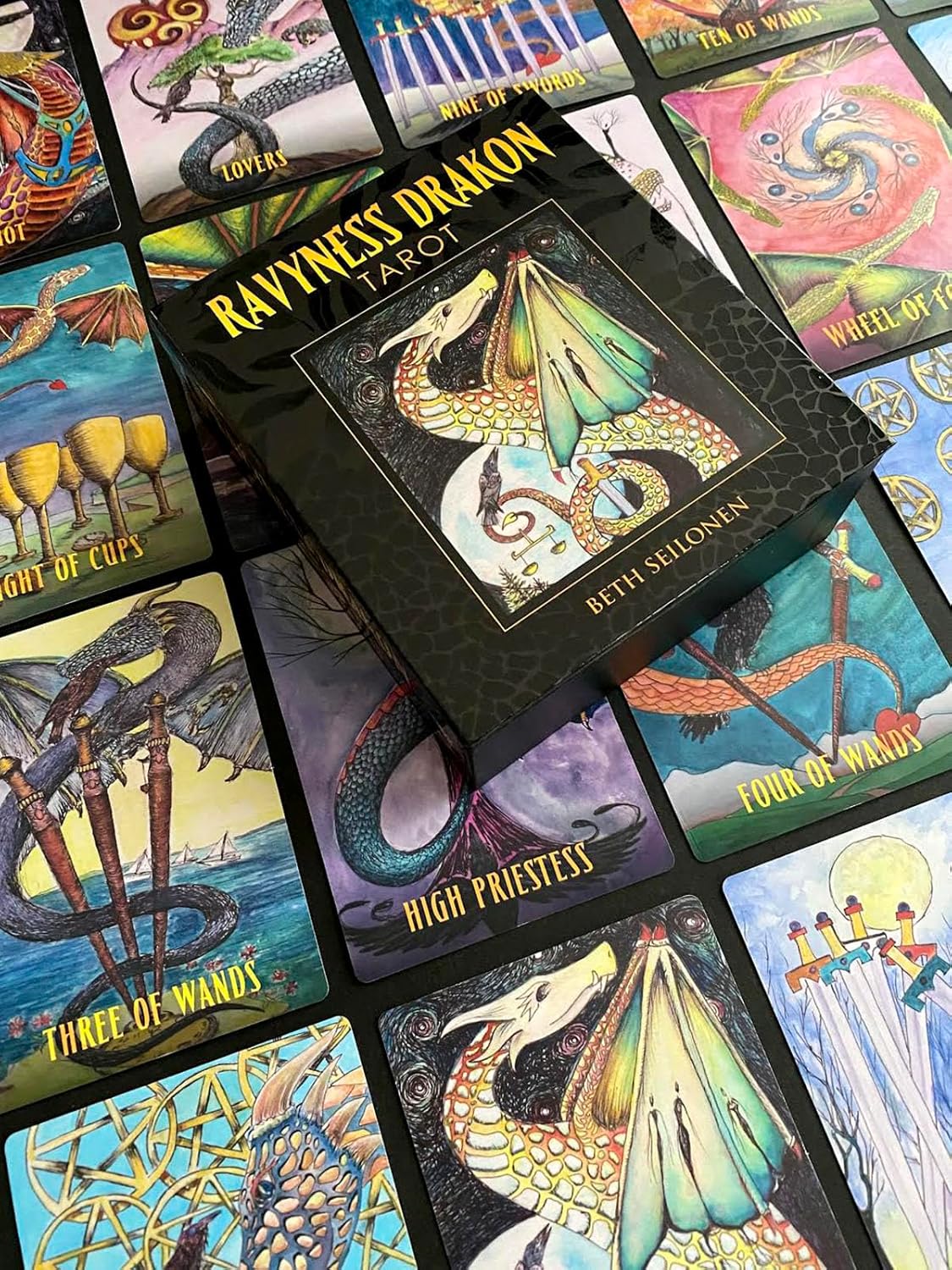 Collection of colorful tarot cards with dragon illustrations and 'Ravyness Drakon Tarot' box.