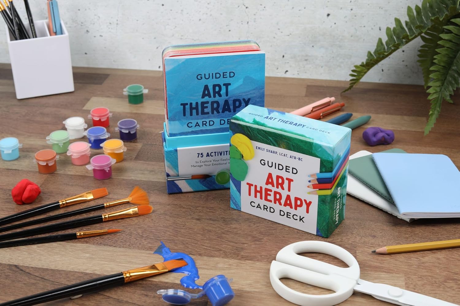 Guided Art Therapy card decks on a wooden table with art supplies.