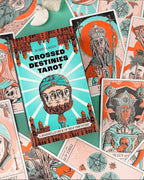 A styled flat-lay of the 'Crossed Destinies Tarot' deck by Bobby Green, featuring the illustrated tarot card 'The World' prominently in the foreground, surrounded by other cards and a mint green background.