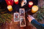 Tarot cards on a wooden table with candles and leaves, indicating a mystical or spiritual setting.