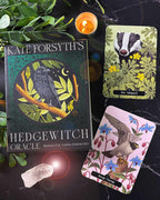 Hedge Witch Oracle book with cards and candle on a dark surface