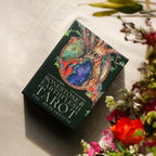 Tarot card box with nature-themed design on a light surface with flowers.