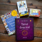 Collection of tarot books and a journal on a wooden surface