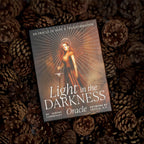 Card titled 'Light in the Darkness Oracle' on a background of pine cones