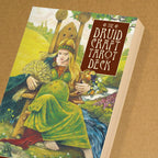 Book cover of 'The Druid Craft Tarot Deck' with a woman in a green dress sitting outdoors.
