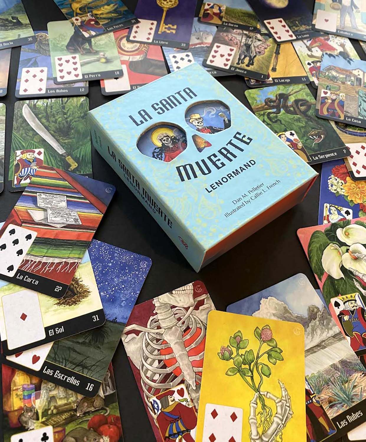 Collection of tarot cards and a blue box labeled 'La Santa Muerte Lenormand' on a dark surface.