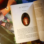 Open book with a decorative page featuring a portrait of a woman with red hair, surrounded by text.