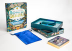 The Illustrated Bestiary book set displayed on a white background, including the illustrated book, an open teal box with a blue ribbon, a blue drawstring pouch, and a tarot card deck.