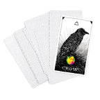Playing card with a crow design and rainbow heart, surrounded by protective card sleeves.