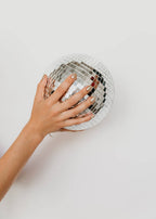 Hand touching a disco ball on a white background