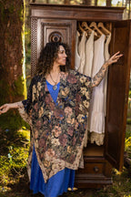 Woman in a floral kimono standing in front of an open wardrobe in a forest setting