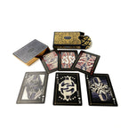A set of illustrated playing cards arranged on a white background, including a top card deck box, a separate card deck, and several face-up cards with black, gold, red, and blue fantasy-style artwork.