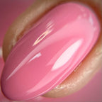 A close-up of a glossy pink nail polish swatch on an artificial nail tip, showing a smooth gradient from medium pink to lighter pink with white highlights.