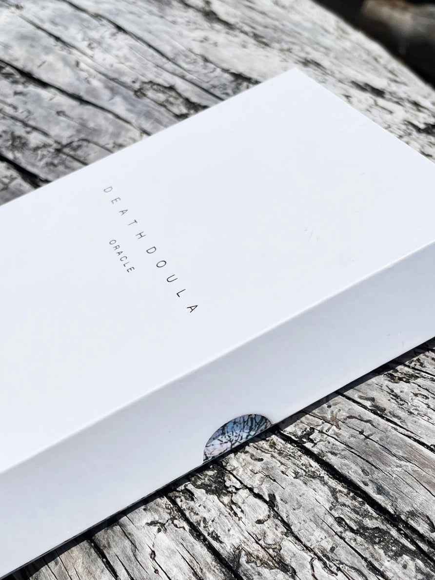 White card with 'DEATH DOULA' text on a wooden surface