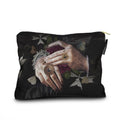 Pouch with artistic design of hands holding a tiara, surrounded by flowers and stars on a black background.