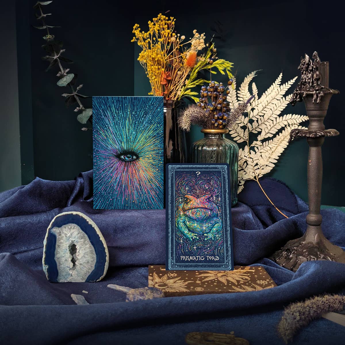 Decorative setup with tarot cards, plants, and a candle on a dark background